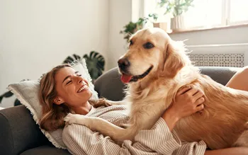 Frau kuschelt mit Hund auf großem Sofa